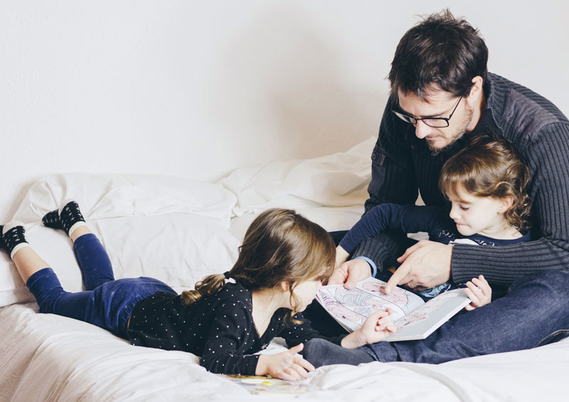 padre leyendo con sus hijas
